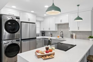 A modern kitchen with stainless steel appliances, a central island with food items, and pendant lighting.