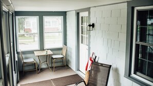 Ein Zimmer mit einem Tisch und zwei Stühlen, sowie mehrere Korbstühle, darunter auch welche mit Kissen.