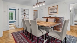 A dining area with a wooden table, six chairs, a patterned rug, and a chandelier. - Spacious Riverfront Home 7 Minutes to Stratton! (Jamaica)