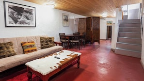 A furnished living room with a sofa, a coffee table, and a dining area with chairs and a table. - Historic Adobe Abode-Pet Friendly, Downtown Kanab (Kanab)