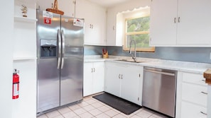 A modern kitchen with white cabinets, stainless steel appliances, a built-in dishwasher, and a window above the sink. - Historic Adobe Abode-Pet Friendly, Downtown Kanab (Kanab)