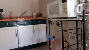 A kitchen with white cabinets, a microwave, a coffee maker, and a water dispenser.