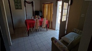 A dining area with a red table and chairs, a television, and a window with curtains.