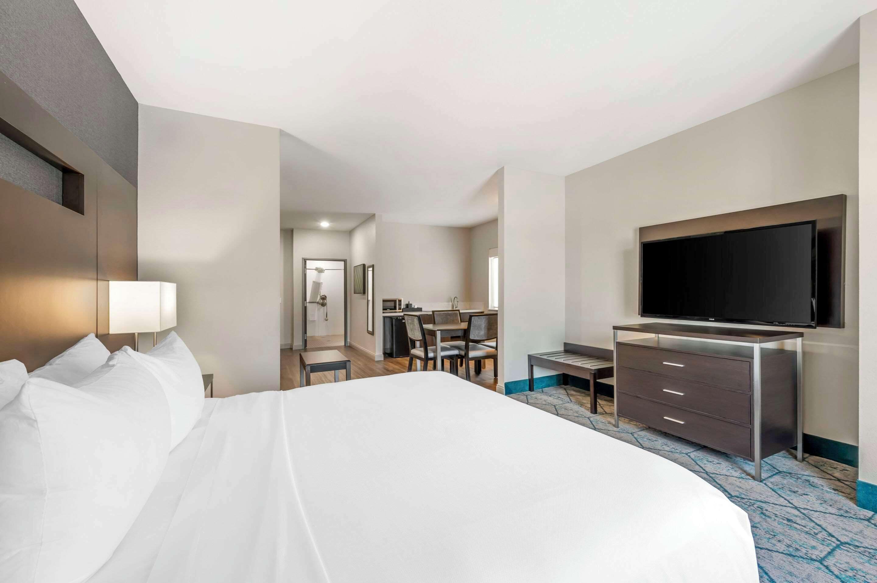 Una habitación de hotel con una cama grande, televisión, escritorio y un baño a la vista.