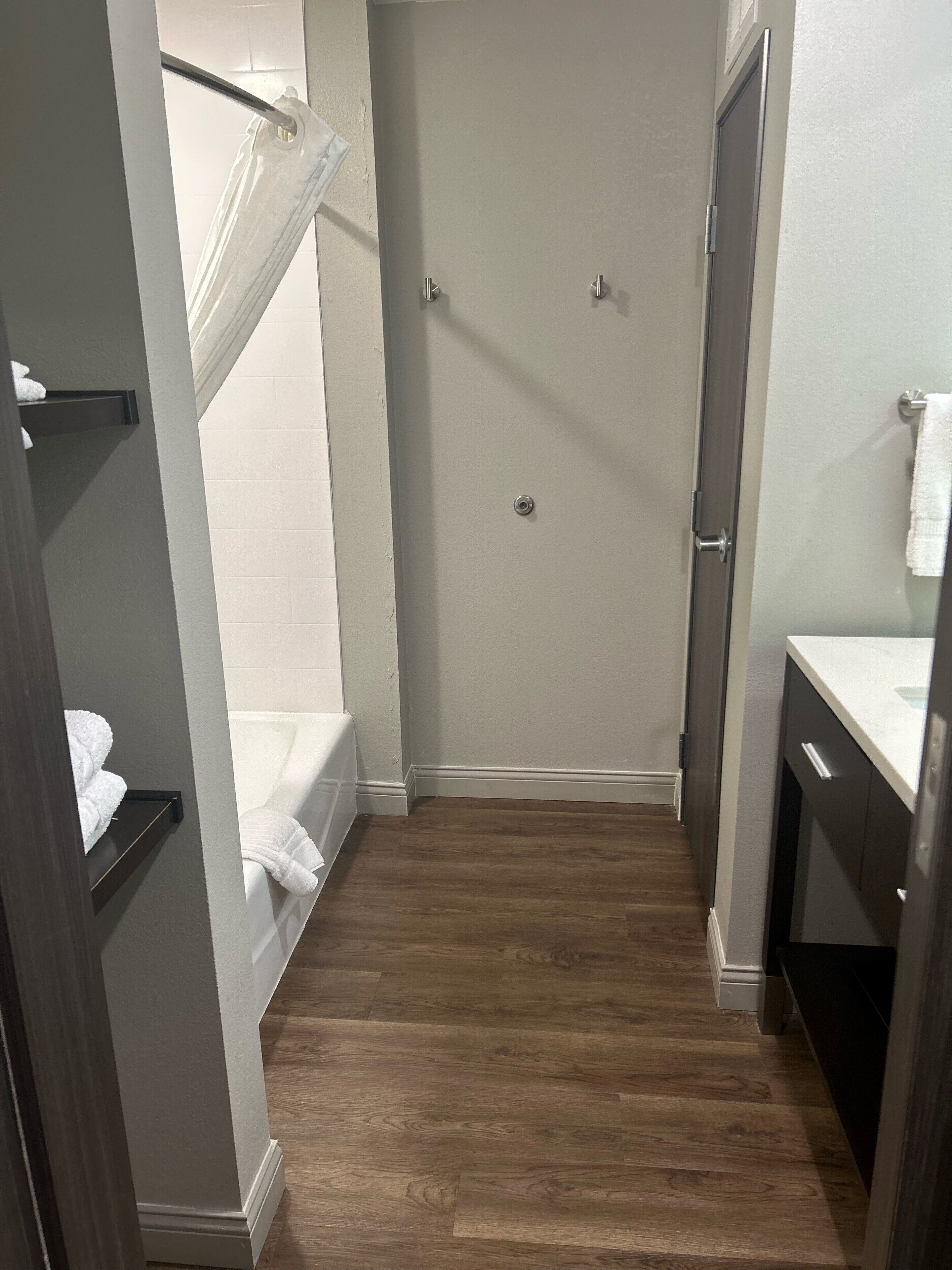 A narrow bathroom with a shower, a bathtub, and a sink.