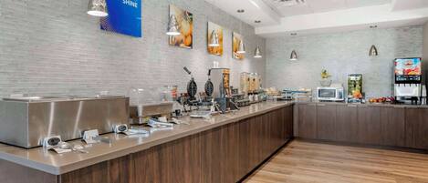 Una barra de desayuno moderna con electrodomésticos de acero inoxidable, un letrero azul y piso de madera.