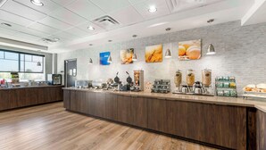 A modern breakfast bar with a wooden floor, a white-tiled backsplash, and various breakfast items displayed. - Comfort Inn & Suites Clarksville - Louisville North (Clarksville)