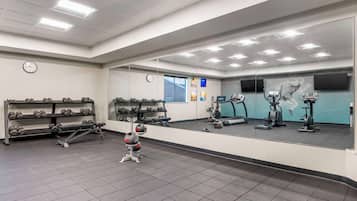 Een sportschool met halterrekken, gewichten, een loopband en fitnessapparatuur.