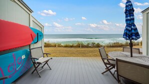 Una terrazza con vista sull'oceano, un'asse da surf coperta e un ombrellone.