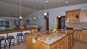 A kitchen with a large island, wooden cabinets, and pendant lighting. -  ORCA HOUSE SPECTACULAR VIEW!! KACHEMAK DRIVE (Homer)