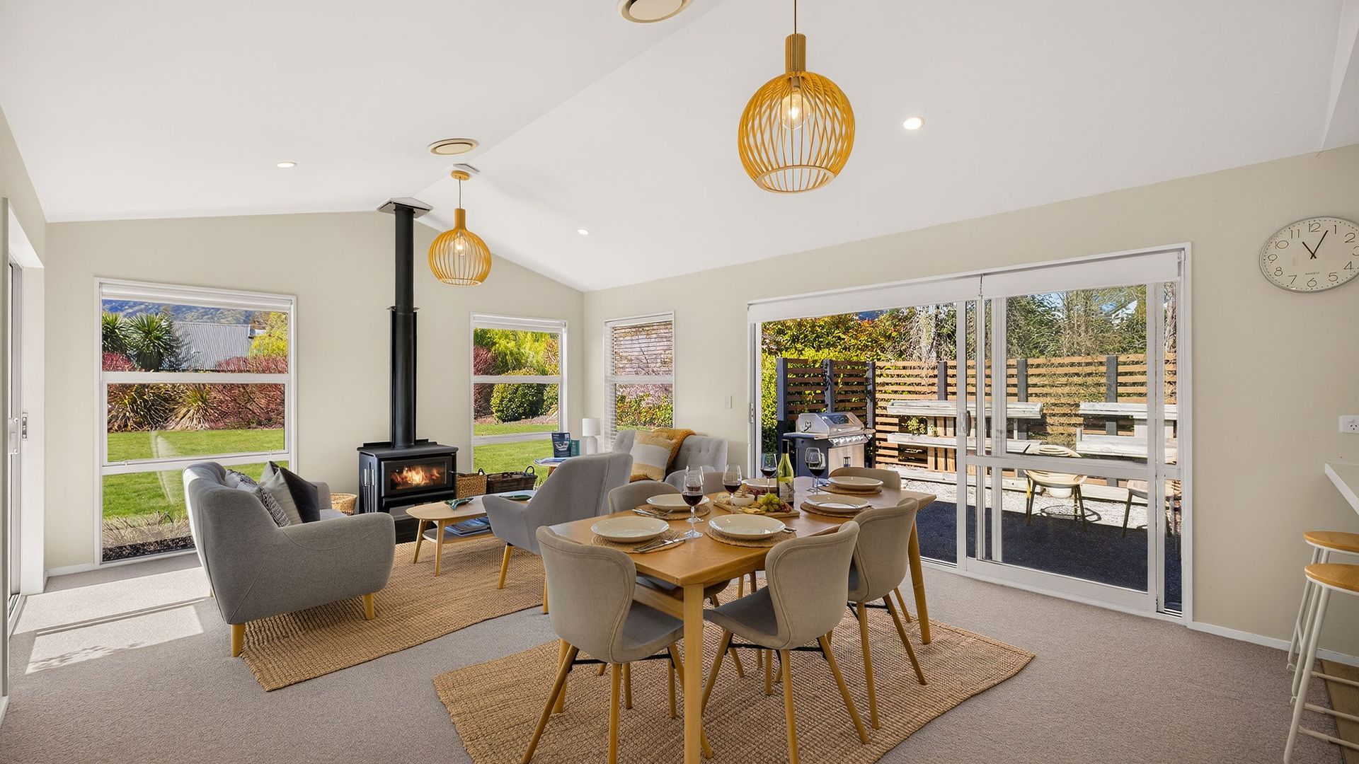 A modern living room with a fireplace, dining area, and large sliding glass doors leading to an outdoor patio.
