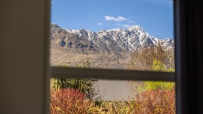 Paisatge de muntanya a través d'una finestra, amb vista a una zona muntanyosa i vegetació al primer terme.