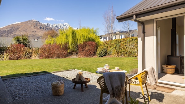 Un patio con mobiliario exterior, una chimenea y vistas a las montañas.