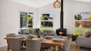 A dining area with a table set for four, a fireplace, and large windows offering a view of the outdoors.