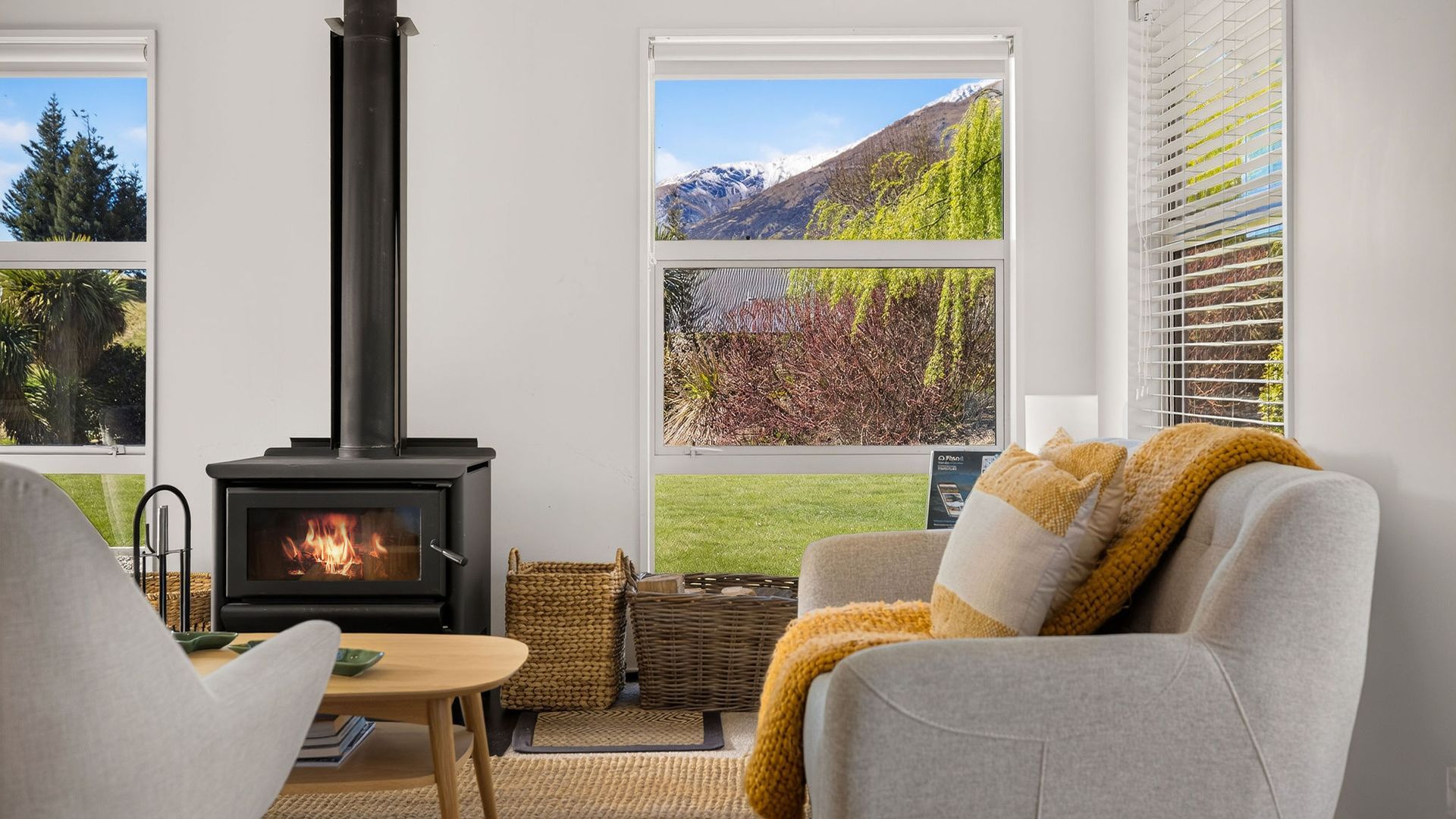 A cozy living room with a fireplace, a sofa, a table, and large windows with a mountain view.