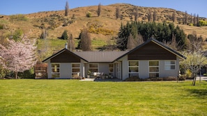 A two-story house with a sloped roof, a front porch, and a well-maintained lawn.