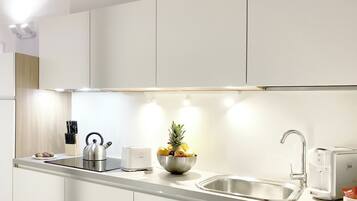 Een moderne keuken met witte kasten, roestvrijstalen apparatuur en een fruitschaal op het aanrecht.