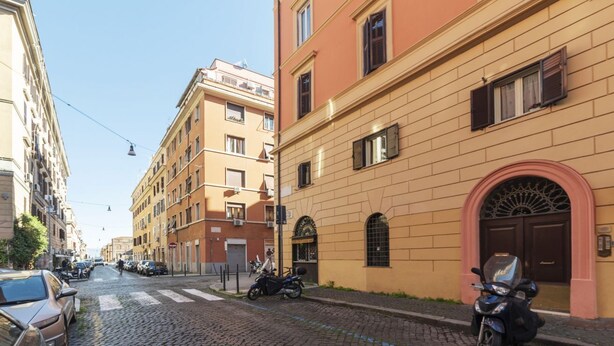 A street with parked cars and motorcycles, buildings with arched windows, and a clear sky. - San Lorenzo Cozy and Comfortable Flat (Rome)