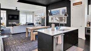 Una cocina moderna con una isla central, muebles negros y luminarias colgantes.
