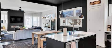 A modern kitchen with a central island, black cabinetry, and pendant lighting.