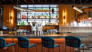 Zona de bar con mostrador, taburetes, estanterías llenas de botellas y un jukebox.