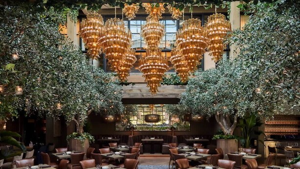 Un restaurante con varias mesas y sillas, un candelabro y plantas.