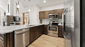 Une cuisine moderne avec des meubles en bois, des appareils électroménagers en acier inoxydable et un lave-vaisselle.
