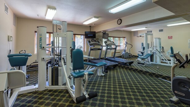 A gym with various exercise equipment, including treadmills, weight machines, and a mirrored wall.