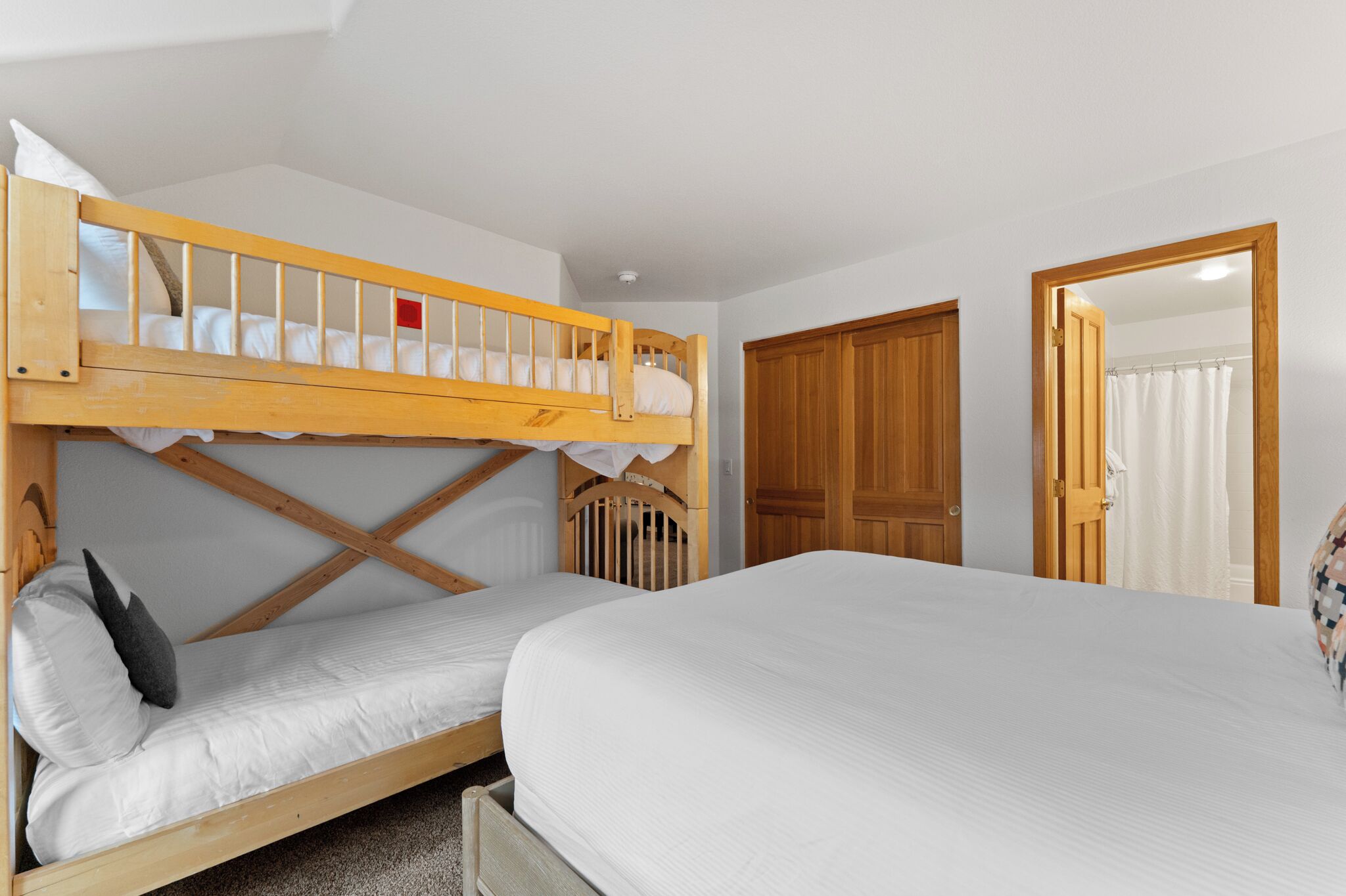 A bedroom with a bunk bed, a single bed, and a wooden door.