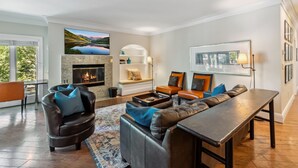 Una sala de estar moderna con chimenea, sofás de cuero, una mesa de centro y un televisor grande.