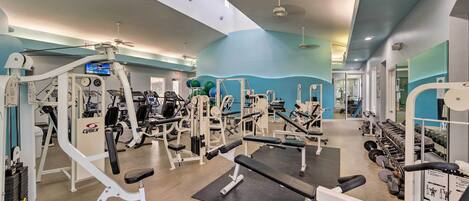 Ett gym med olika träningsmaskiner, en stor spegel och en takfläkt.