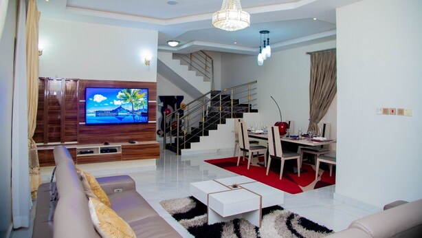 Un salon moderne doté d’un téléviseur à écran plat, d’un canapé, d’une table basse et d’un escalier menant à un espace repas.