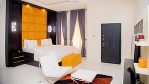 Une chambre d’hôtel moderne avec un grand lit, une table de chevet, une chaise et une armoire.