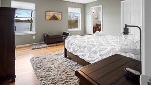 A bedroom with a bed, a wooden nightstand, a fluffy rug, a ceiling fan, and a view of a lake through the windows. - Lakefront Oasis, Dog-Friendly with Boat and Sauna included (Pocono Summit)