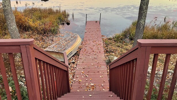 A wooden staircase leading to a dock over a calm lake with autumn foliage. - Lakefront Oasis, Dog-Friendly with Boat and Sauna included (Pocono Summit)