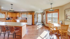 A kitchen with wooden cabinets, a central island with bar stools, and pendant lighting. - Columbia Falls Private Retreat: Pool Table & Deck! (Columbia Falls)