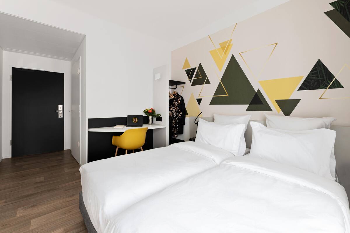 Una habitación de hotel moderna con una cama grande, un escritorio y una silla.