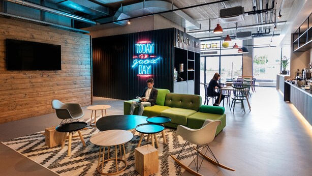 A modern lounge area with a neon sign, green sofa, and round tables. - B&B Hotel Oftringen (Oftringen)