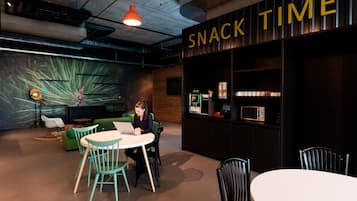 Et moderne loungeområde med et skilt, der siger 'SNACK TIME', siddepladser og en vægmonteret mikroovn.