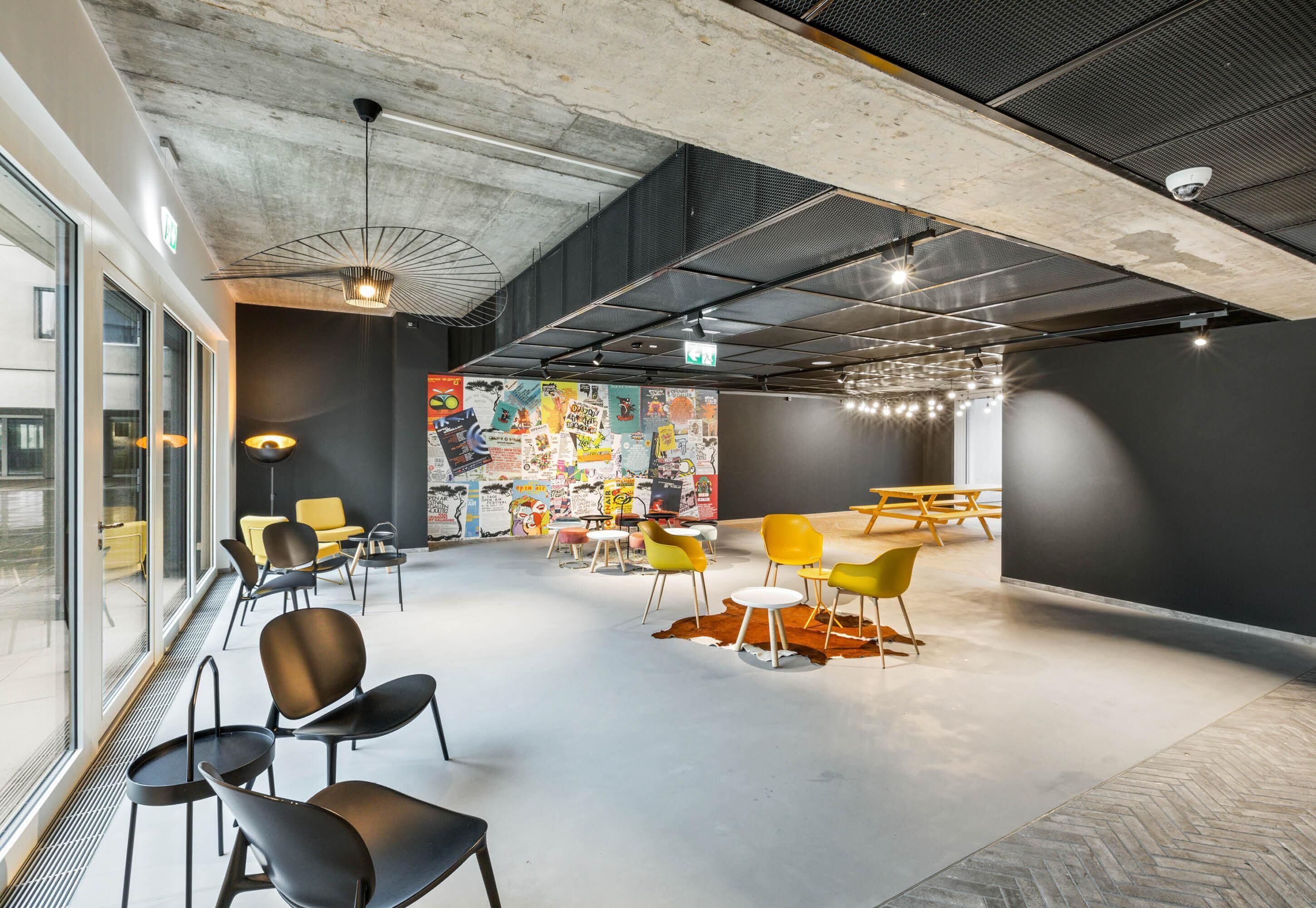 Ein modernes Interieur mit Betondecke, großen Fenstern und einem farbenfrohen Wandgemälde.