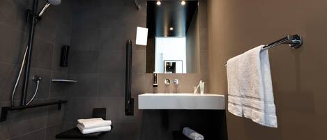A modern bathroom with a shower, sink, and towel rack.
