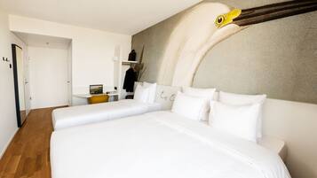 Une chambre d’hôtel moderne avec un grand lit, un bureau et une œuvre d’art représentant un oiseau, accrochée au mur.
