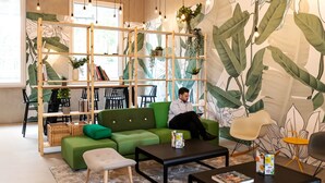 Un área de descanso moderna con un sofá verde, una mesa de centro negra y una estantería de madera.