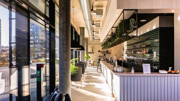 Zona de bar moderna con mostrador, asientos y vista a la calle.