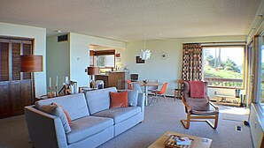 A living room with a sofa, chairs, a coffee table, and a dining area with a table and chairs. - Sea it All - Ocean View Yachats (Yachats)