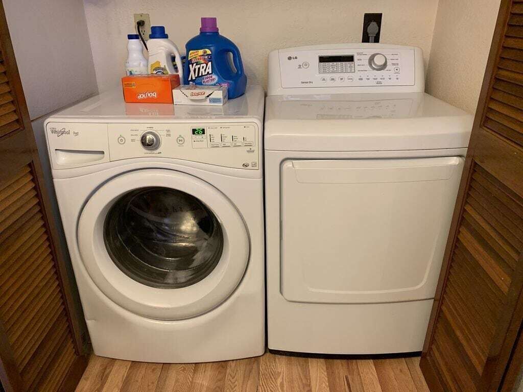 Un área de lavandería con dos lavadoras, una botella de detergente y un panel de control.