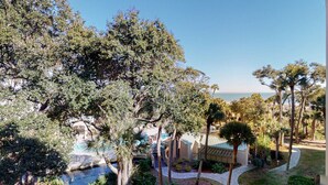 A resort with a pool, palm trees, and a view of the ocean. - Large Two Bedroom Villa with Ocean Views! (Hilton Head)