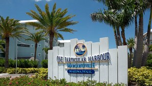Un letrero para One Particular Harbour con un logotipo, el nombre 'Margaritaville' y 'Marina Walk' escrito debajo.