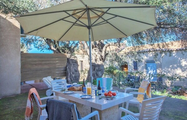An outdoor dining area with a table, chairs, and a large umbrella.