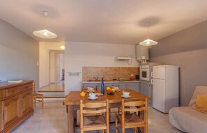A compact living space with a dining area, kitchenette, and a sofa. - Domaine Bollaccia - Casa Bodri (Monticello)
